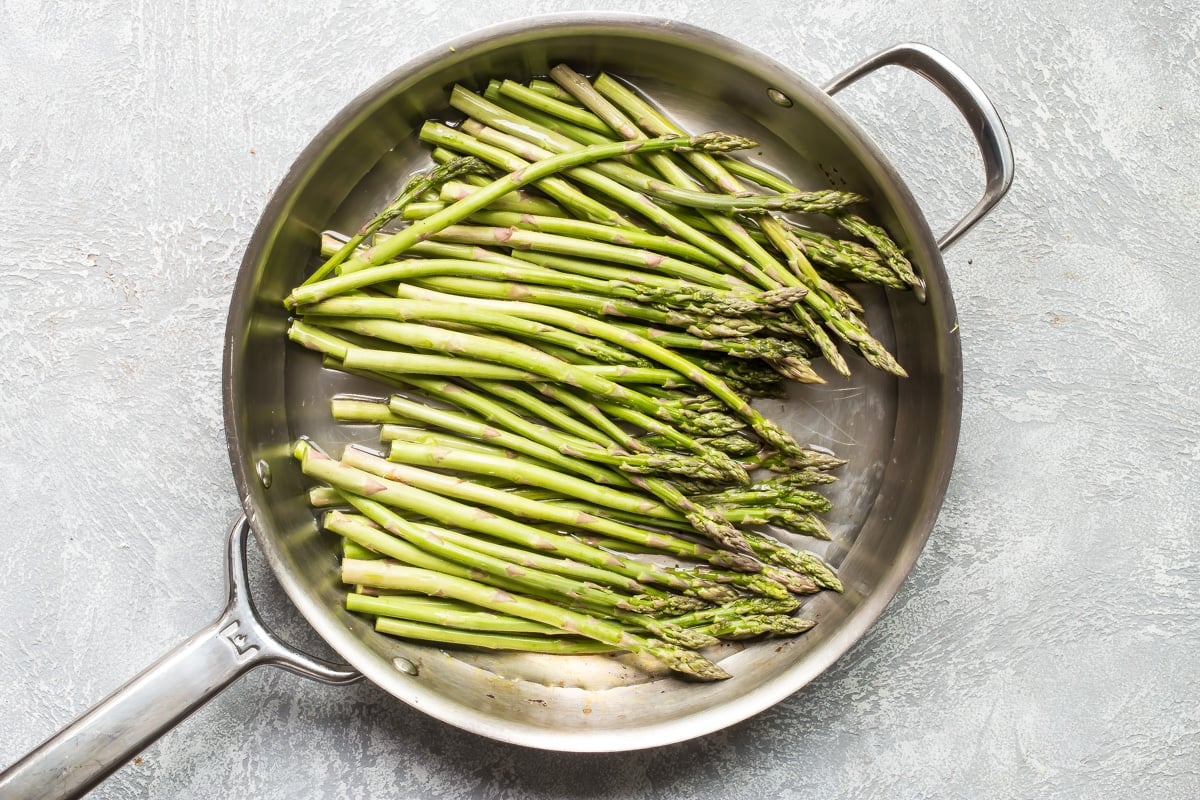 Asparagus in a silver frying pan.