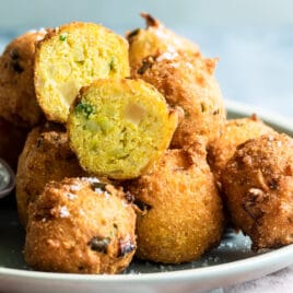 Hush puppies on a light blue plate with white dipping sauce.
