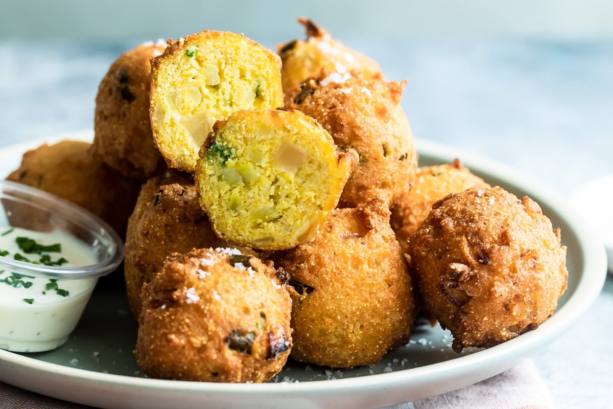 Hush puppies on a light blue plate with white dipping sauce.