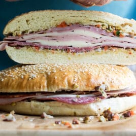 Muffaletta sandwiches on a wooden cutting board.