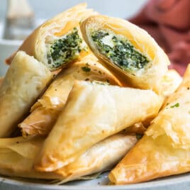 A pile of three cheese spanakopita triangles on a plate.