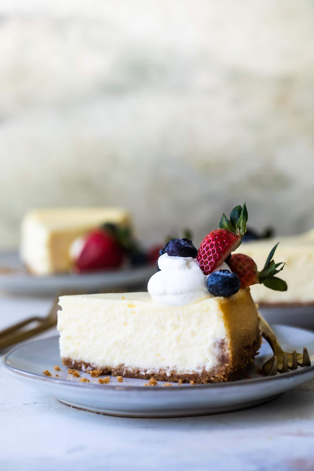 A plate of Vanilla Cheesecake with berries and whipped cream on top.