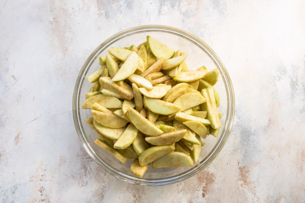 Apple pie mixture in a glass bowl.