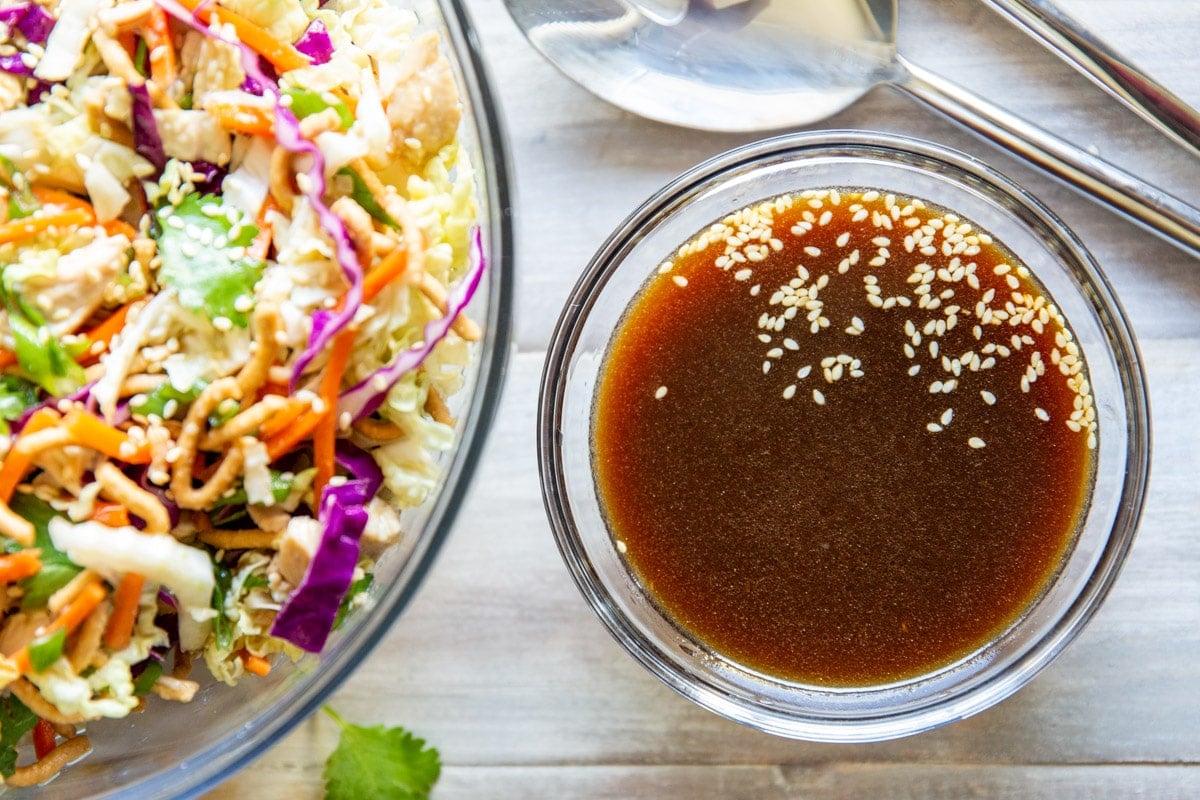 A bowl of Asian Salad Dressing sitting in front of a bowl of Chinese Chicken Salad.