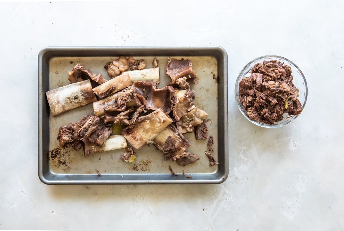 Short rib remnants on a baking sheet after meat has been picked off of bones.