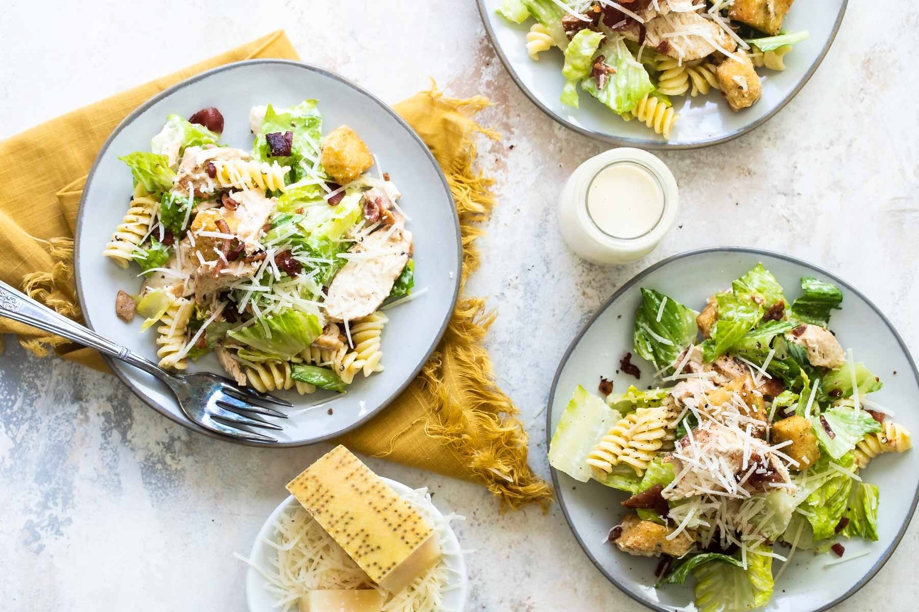 Three plates of chicken Caesar pasta salad.