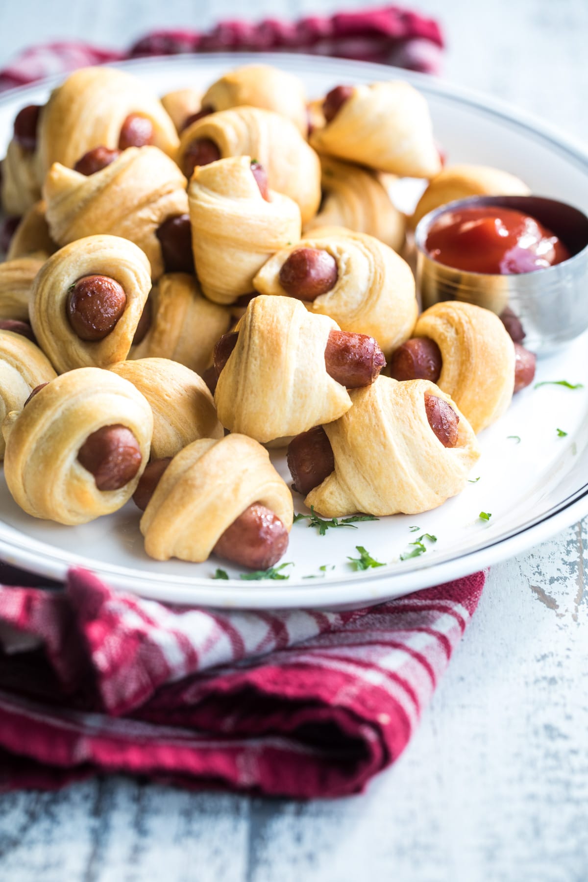 Easy pigs in a blanket on a white plate with a side of ketchup.