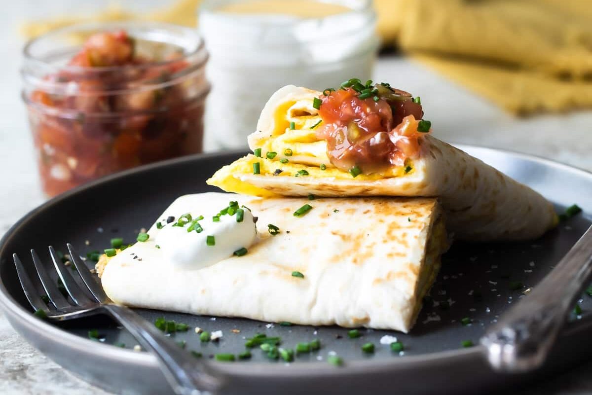An egg burrito stacked on a gray plate.