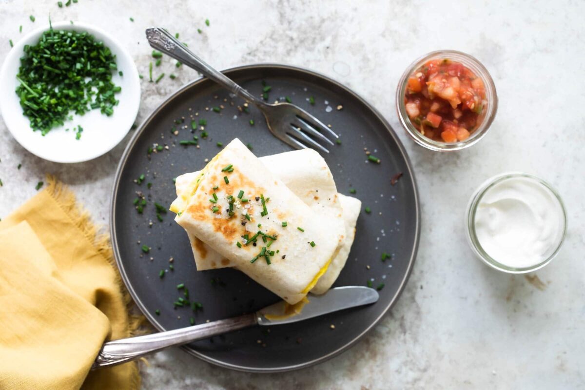 Egg burritos stacked on a gray plate.