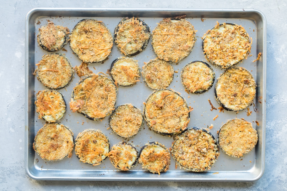 Slices of eggplant on a sliver baking sheet.
