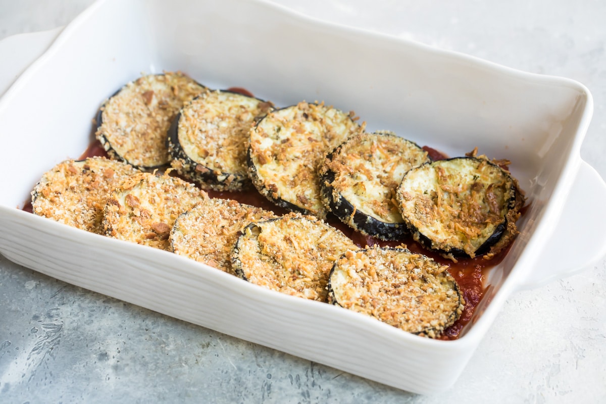 Slices of eggplant in a white baking dish.