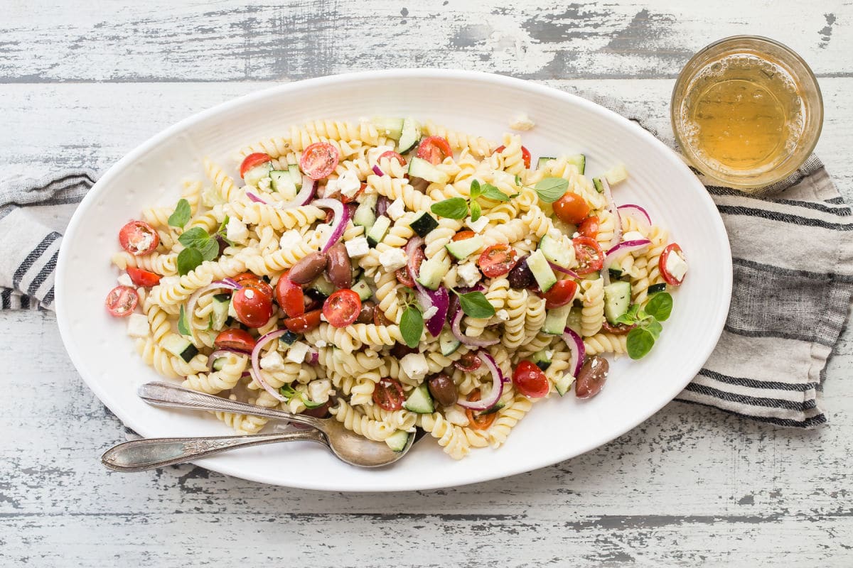 Greek pasta salad in a white bowl.