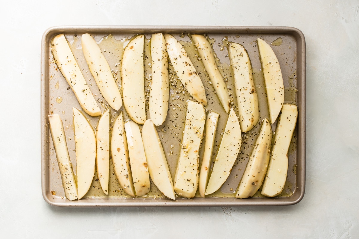 Precooked greek roasted potatoes on a baking pan.