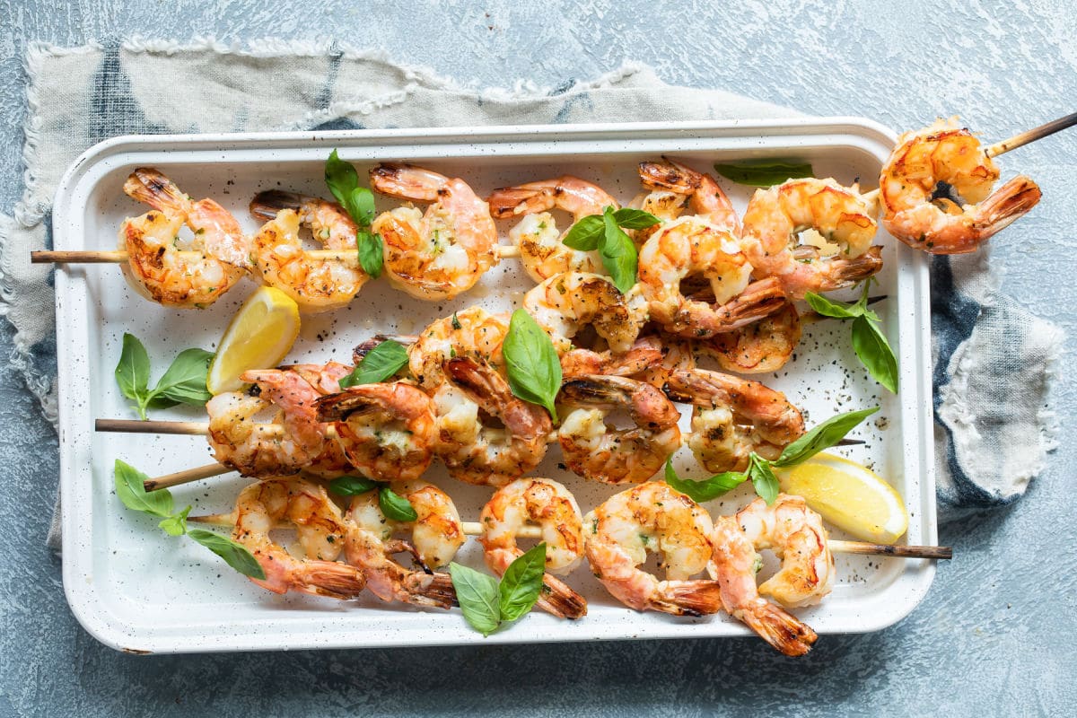 Grilled shrimp skewers in a white tray.