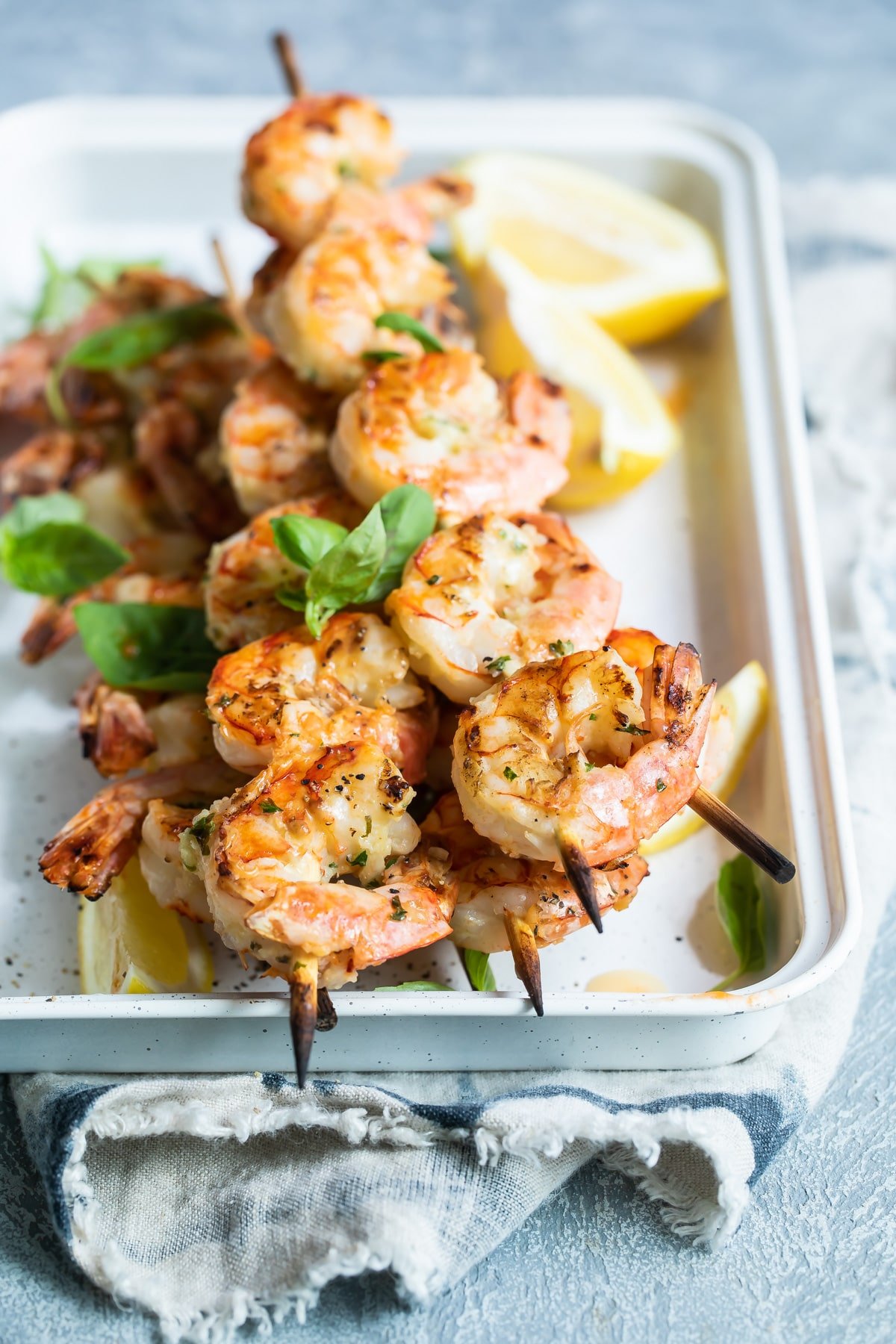 Grilled shrimp skewers in a white tray.