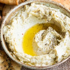 Homemade hummus with zaatar butter in a bowl with pita chips.