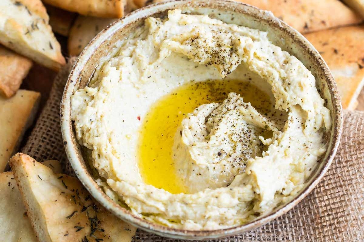 Homemade hummus with zaatar butter in a bowl with pita chips.