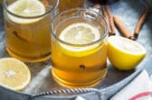 Hot toddies in clear glass mugs on a silver serving tray.