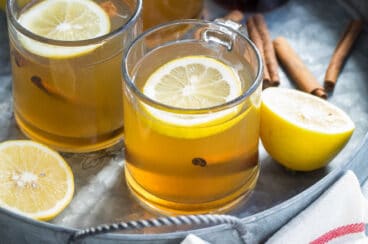 Hot toddies in clear glass mugs on a silver serving tray.