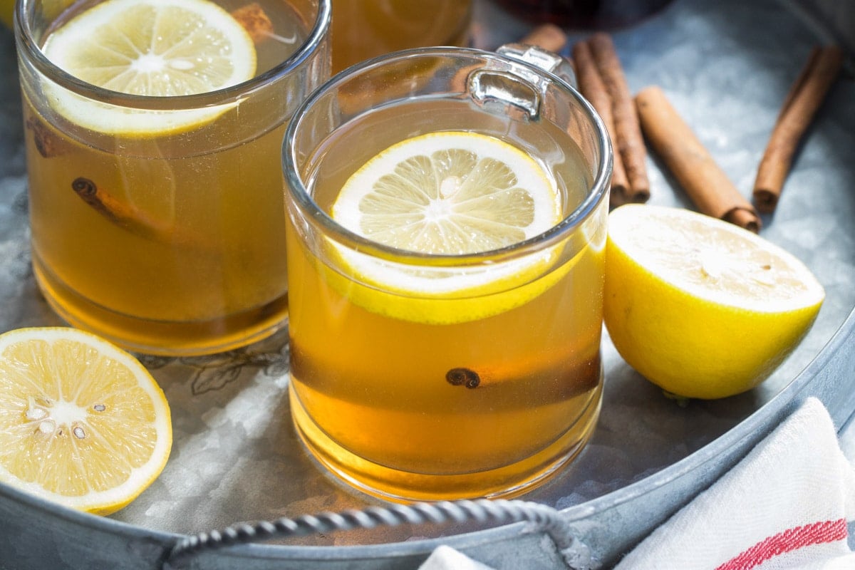 Hot toddies in clear glass mugs on a silver serving tray.