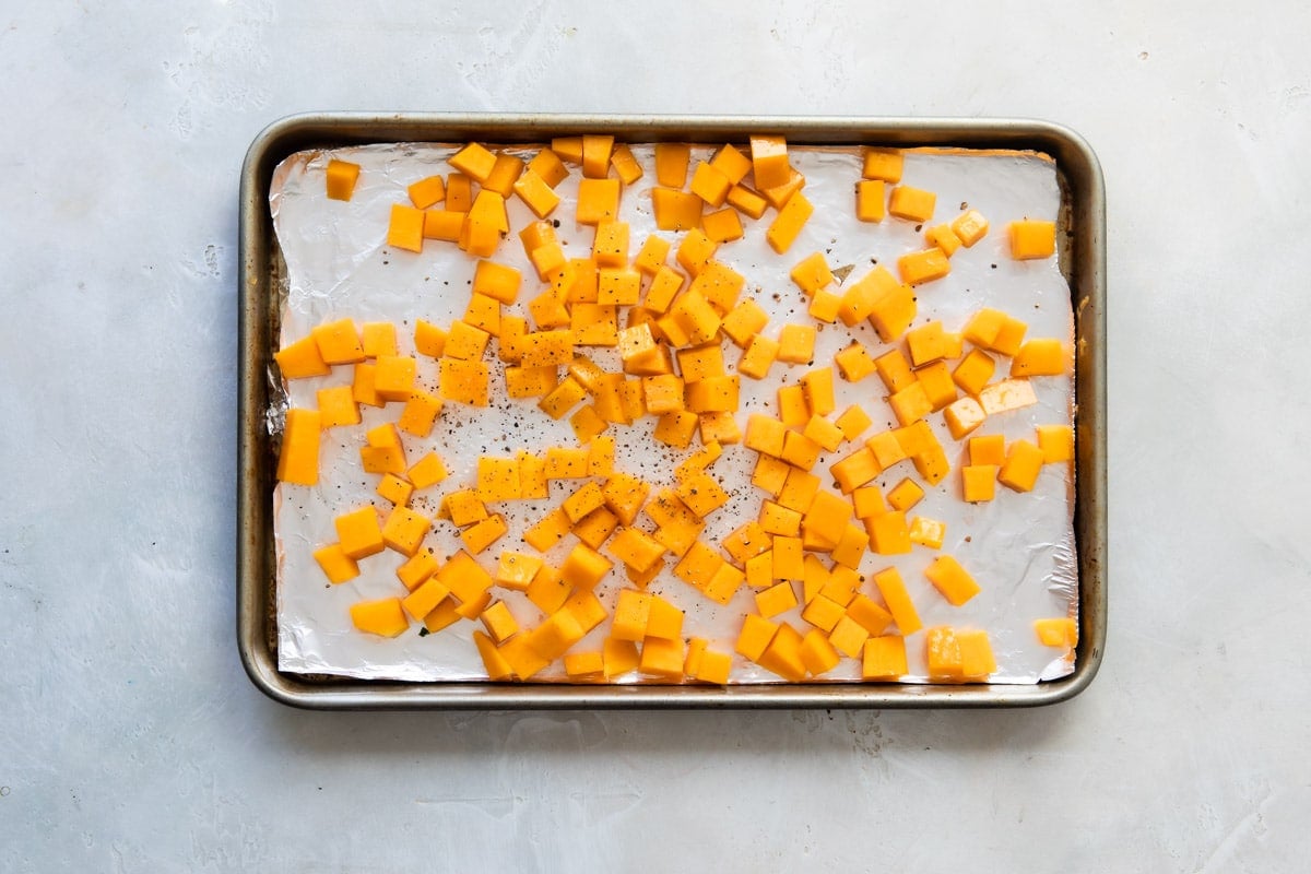 Butternut squash on a baking sheet before being roasted.