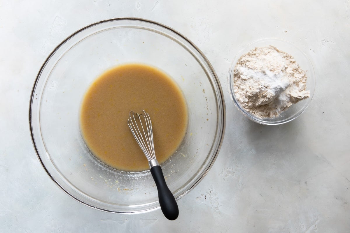 Wet ingredients and dry ingredients for lemon olive oil cake in two bowls.