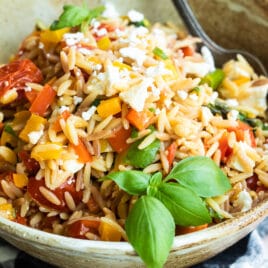 Orzo pasta salad in a bowl with a spoon.