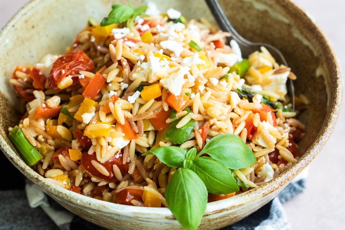 Orzo pasta salad in a bowl with a spoon.