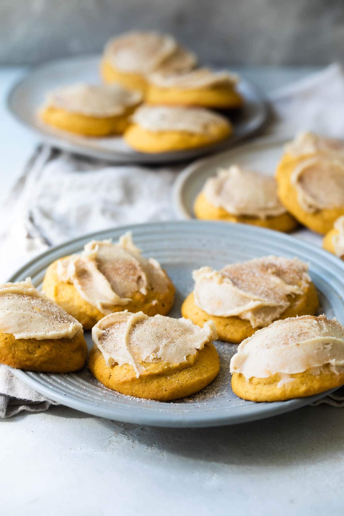 Three plates of frosted pumpkin cookies.