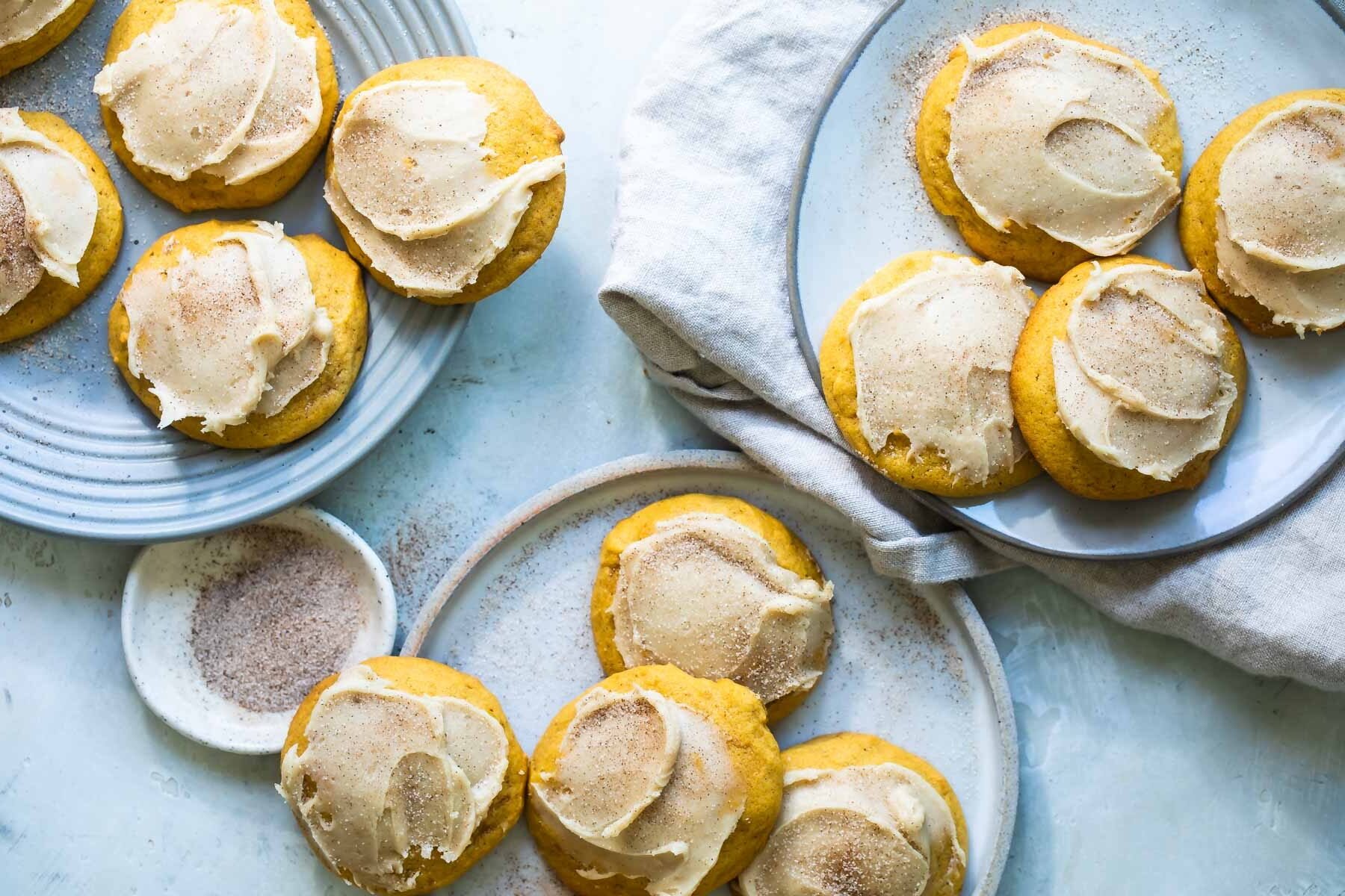 Three plates of frosted pumpkin cookies.