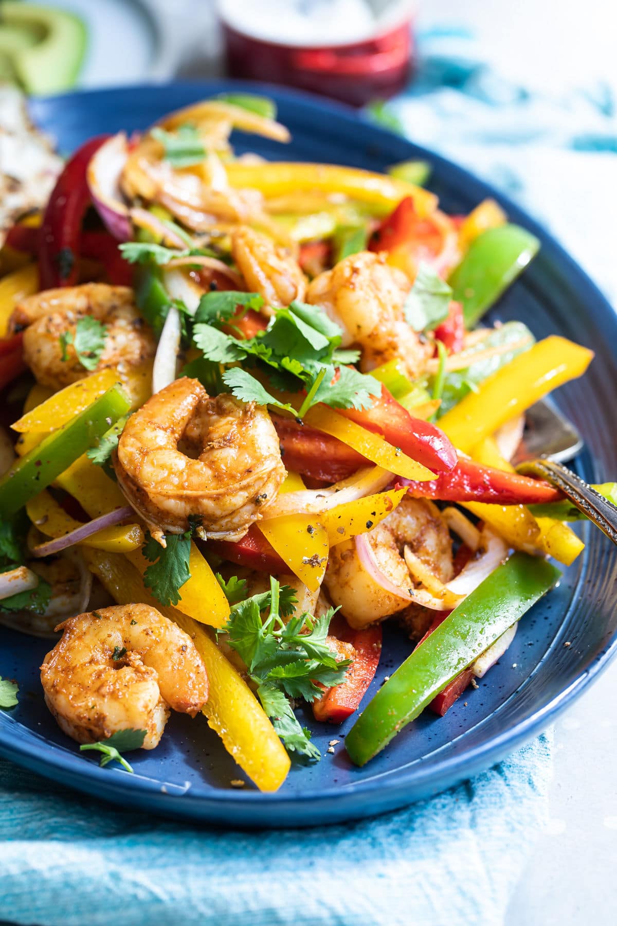 Shrimp fajitas on a blue plate with a side of rice and flour tortillas.