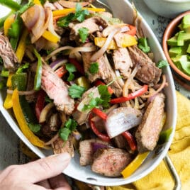 Steak fajitas in a white serving dish.