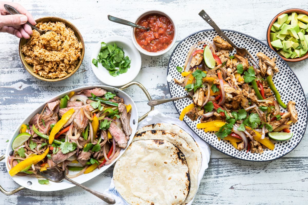 Chicken and steak fajitas on two serving platters.