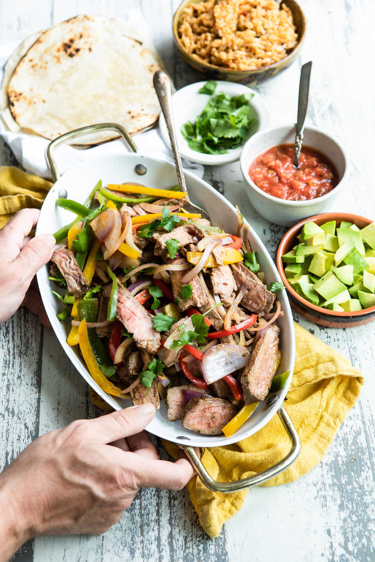 Steak fajitas in a white serving dish.