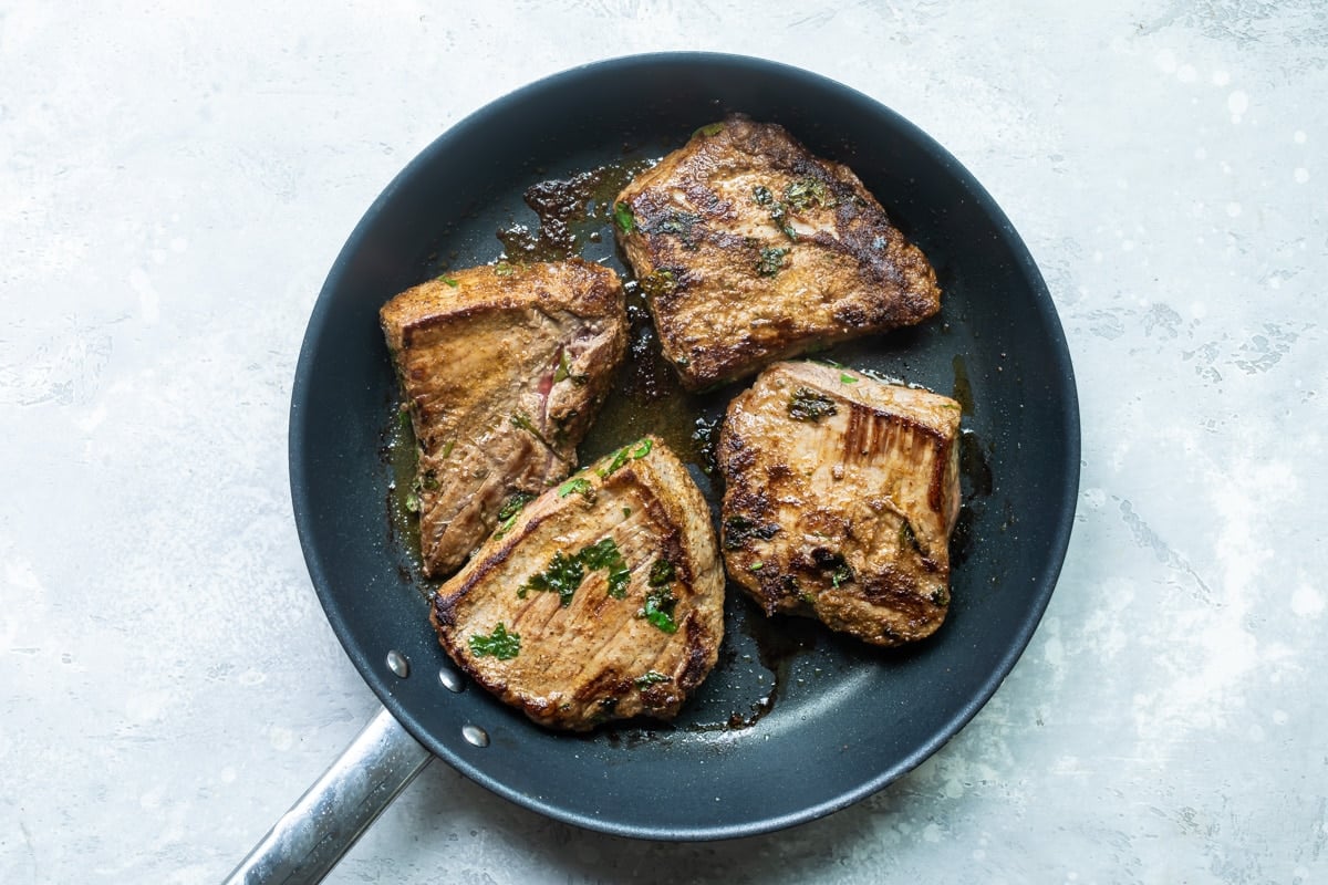 Steak searing in a black skillet.