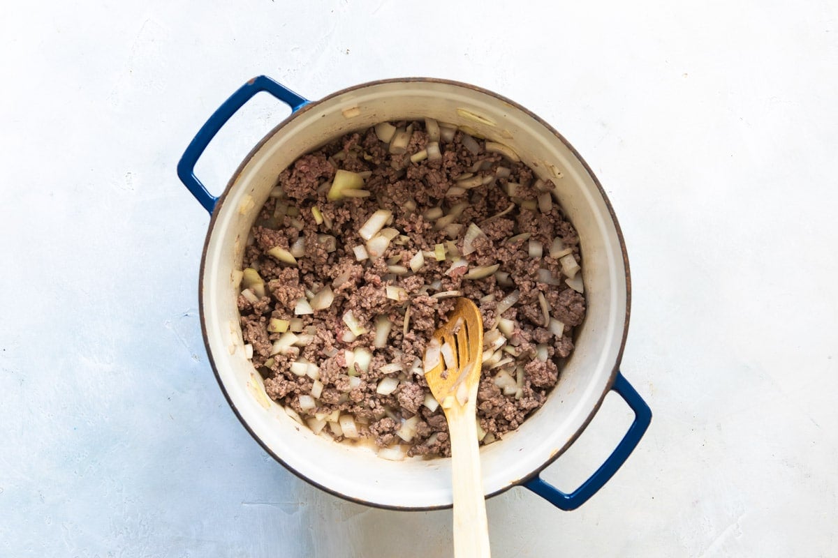 Ground beef and onions browning in a Dutch oven.
