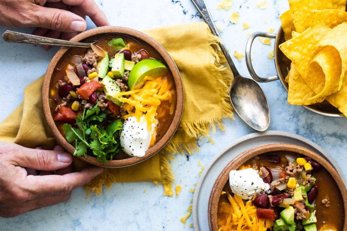 Two bowls of taco soup in brown bowls.