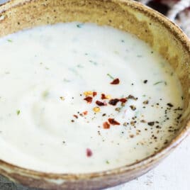 A small brown bowl filled with yogurt sauce.