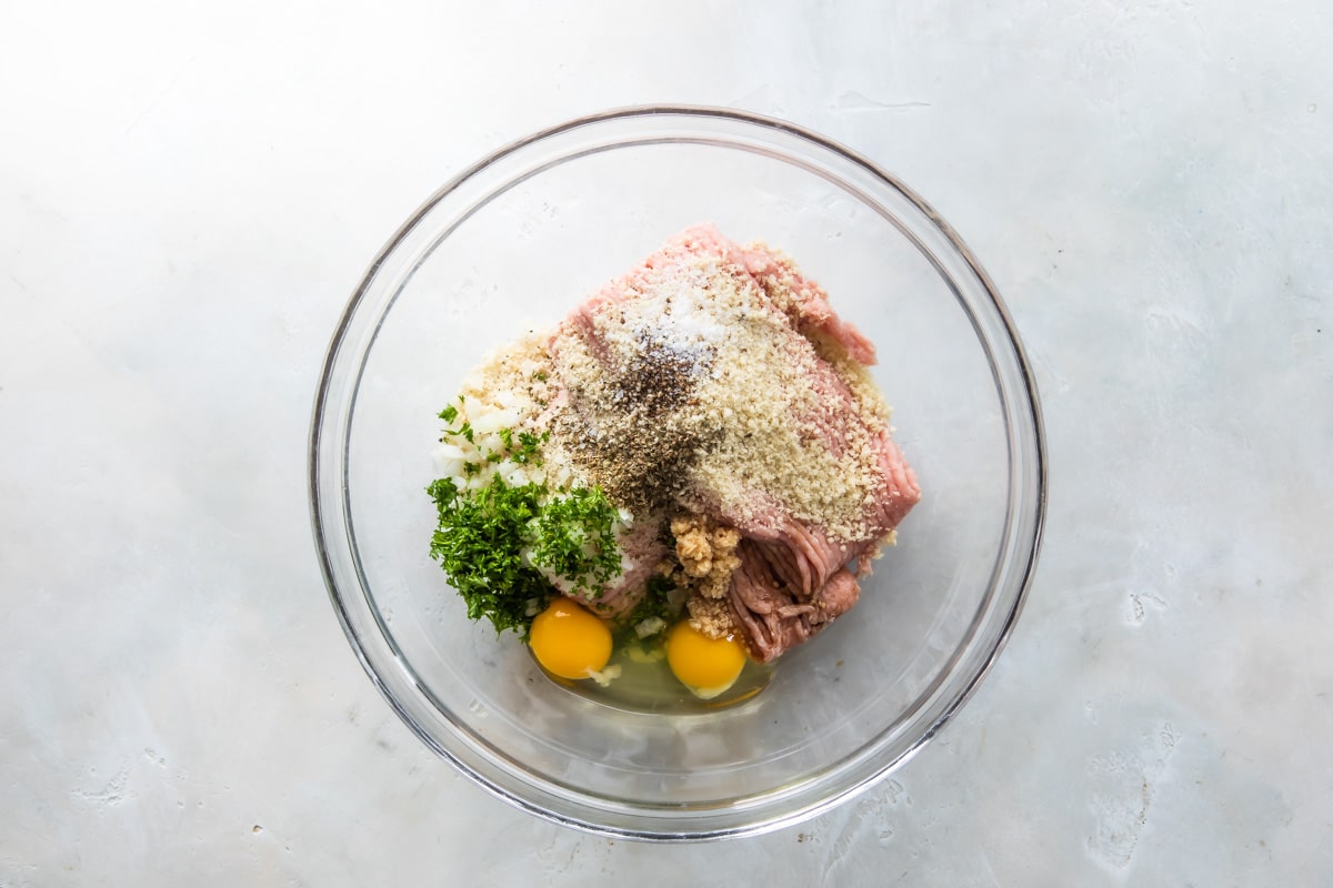 Ingredients for air fryer meatballs in a clear bowl.