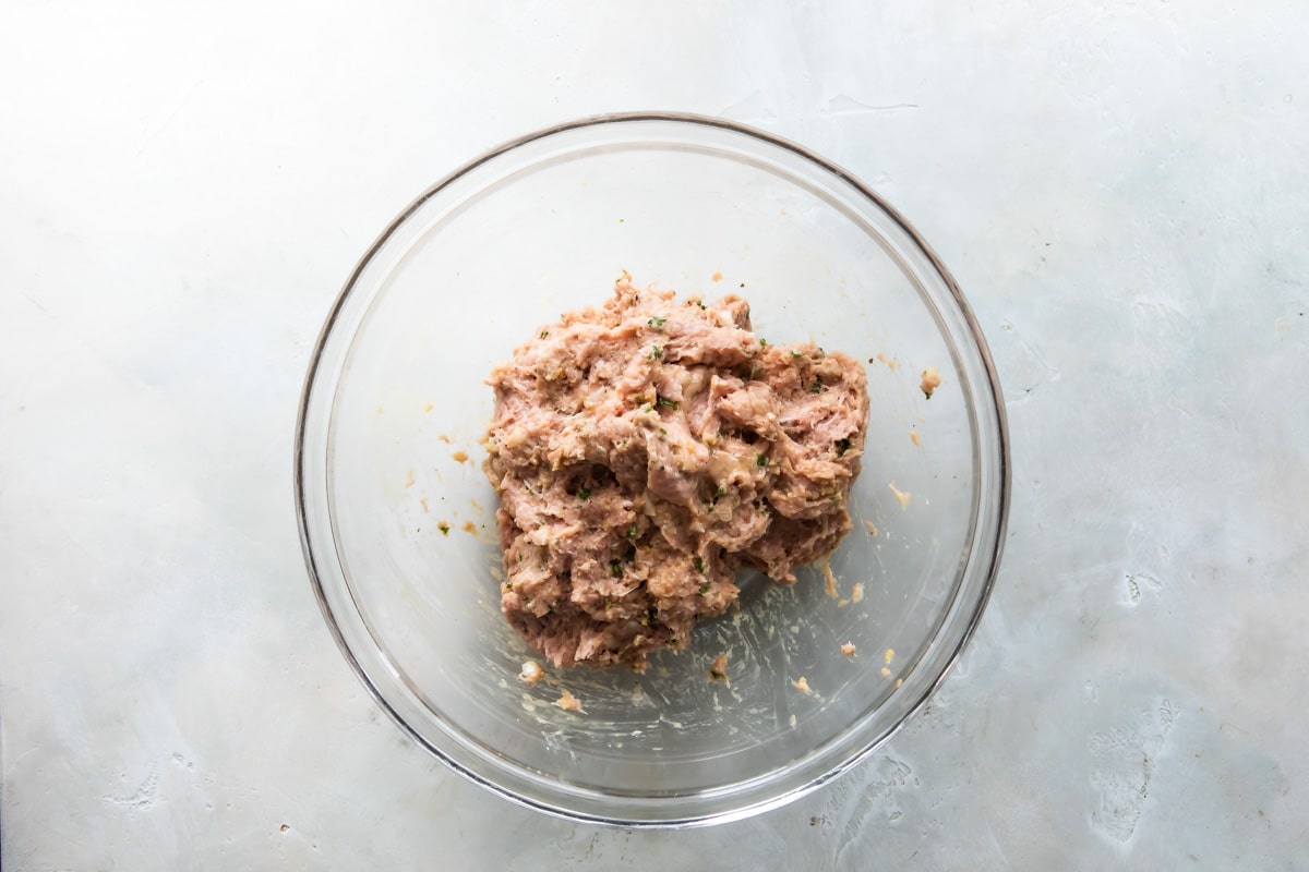Air fryer meatball ingredients mixed together in a clear bowl.