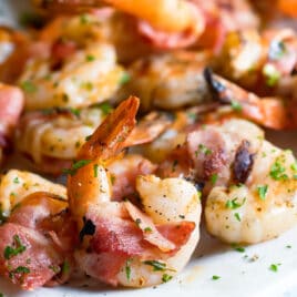 Bacon wrapped shrimp on a white platter.