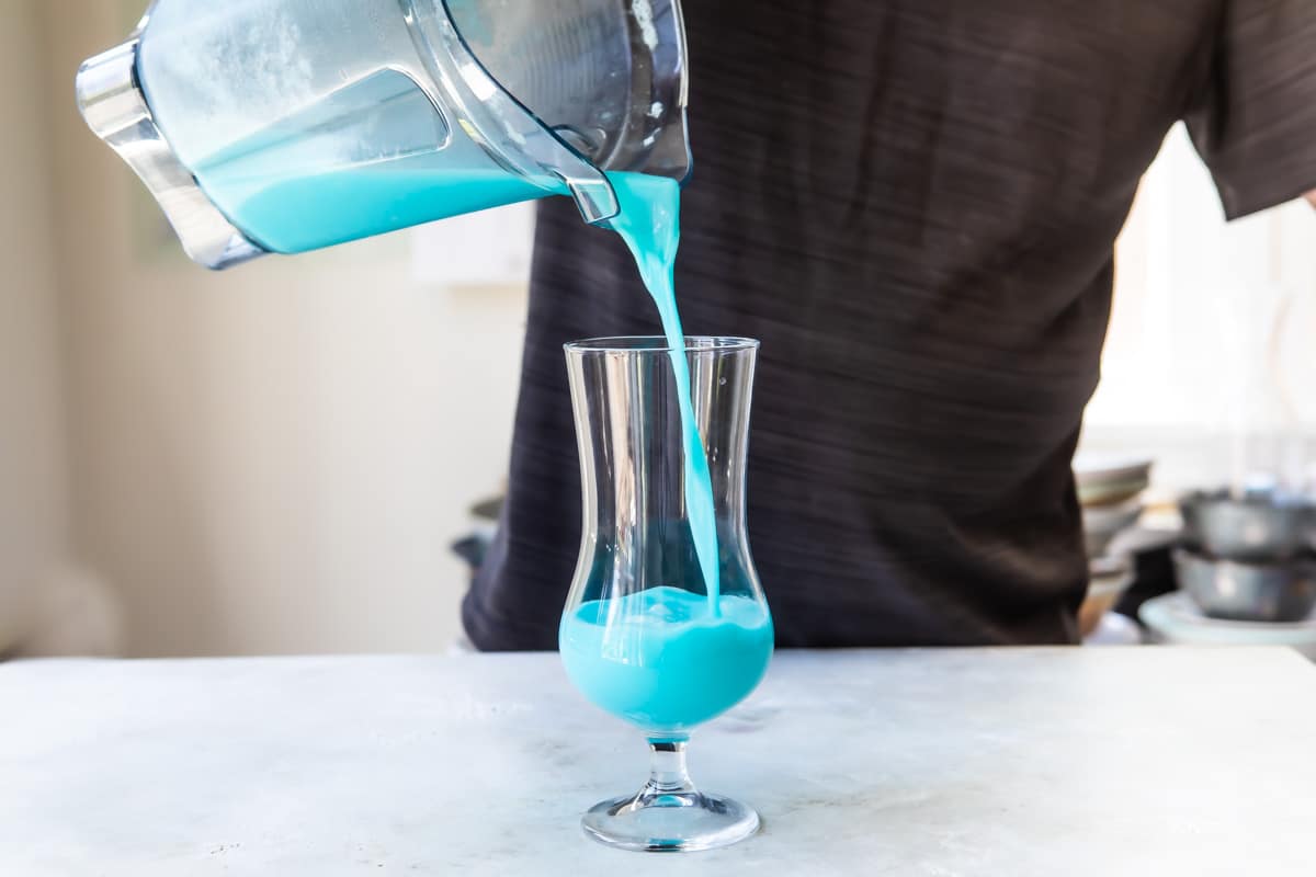 Pouring a Blue Hawaiian cocktail into a glass.