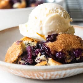 Two plates of blueberry cobbler with ice cream.