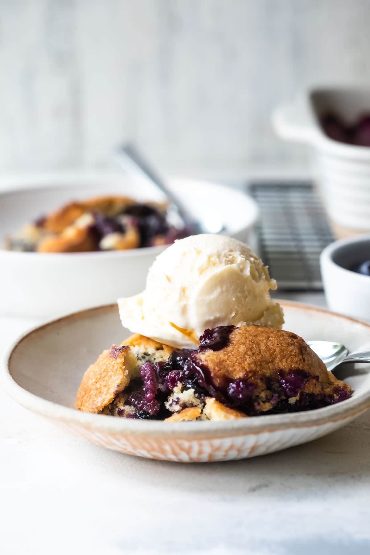 Two plates of blueberry cobbler with ice cream.