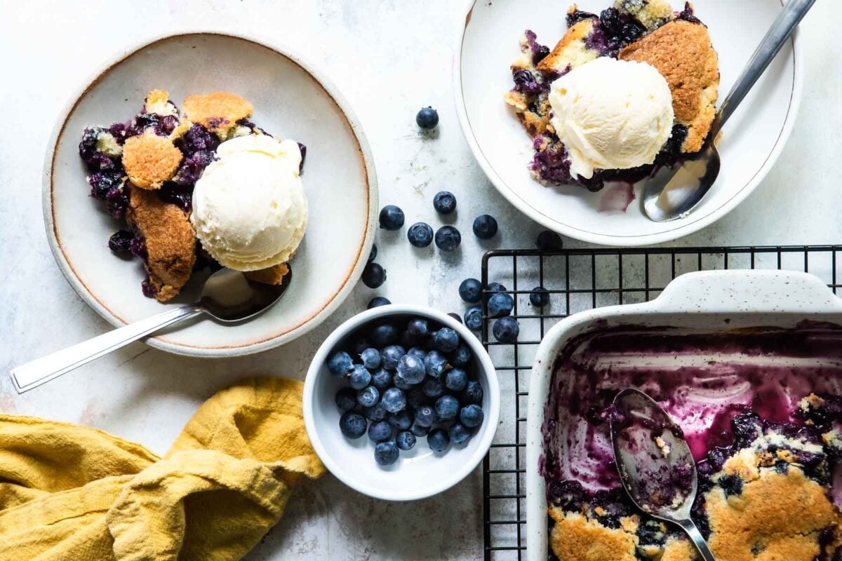 Two plates of blueberry cobbler with ice cream.