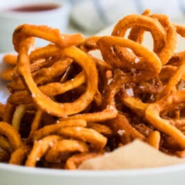 Curly fries in a white bowl.