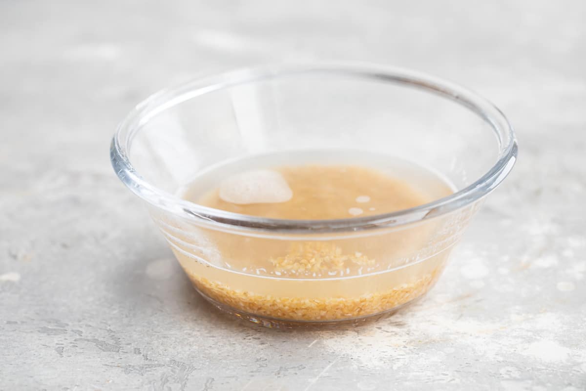 Bulgur being soaked in water in a clear bowl.