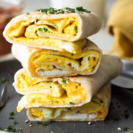 Egg burritos stacked on a gray plate.