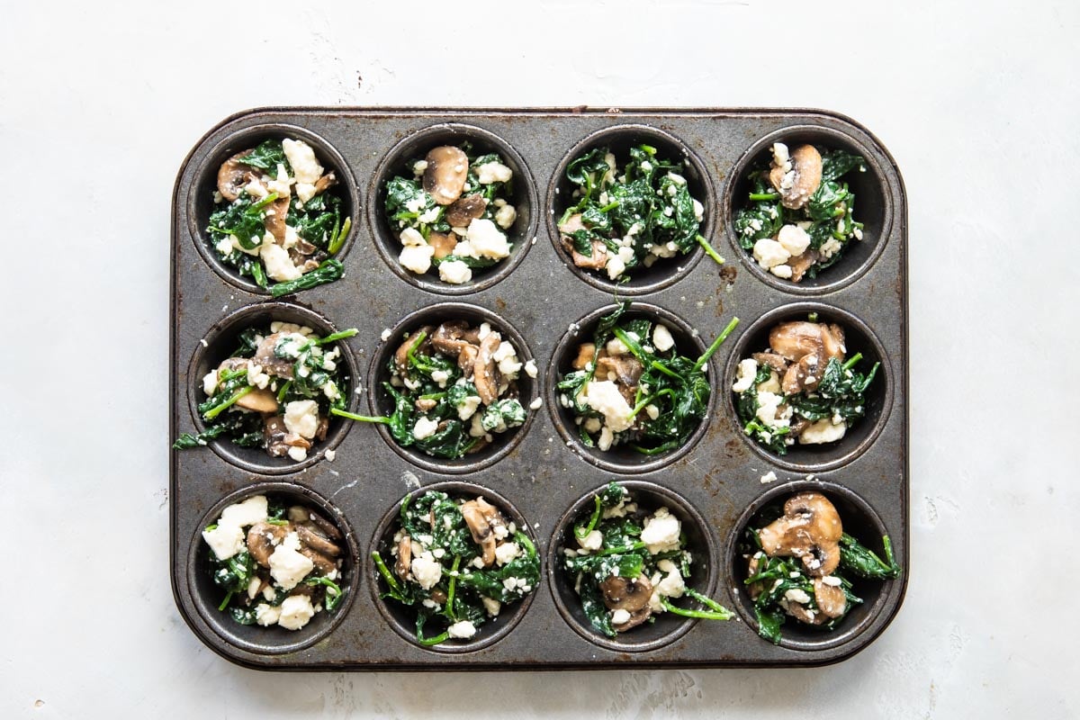 A muffin tin with egg muffin mixture ingredients.