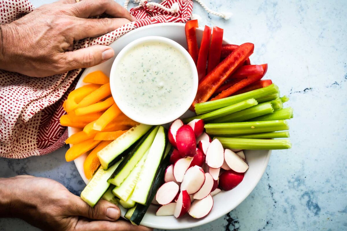 A veggie platter with a dish of green Goddess dressing.